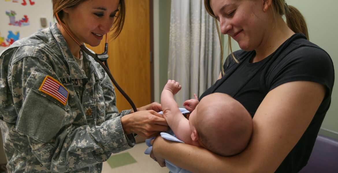Army doctor examines baby held by its mother