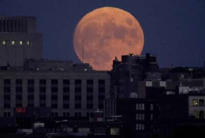 The full harvest moon rises behind downtown buildings, Friday, Sept. 9, 2022, in Kansas City, Mo. (AP Photo/Charlie Riedel)